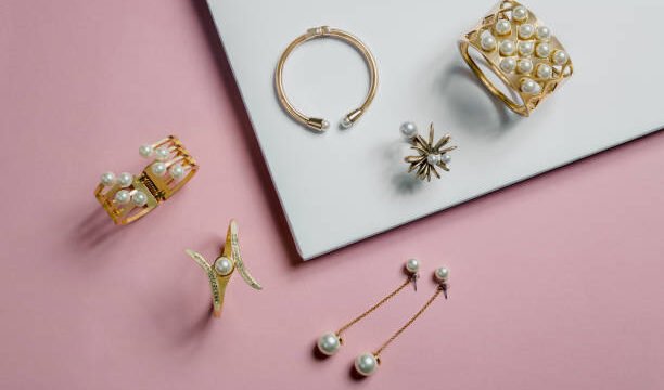 golden bracelets and earrings on pink and white background